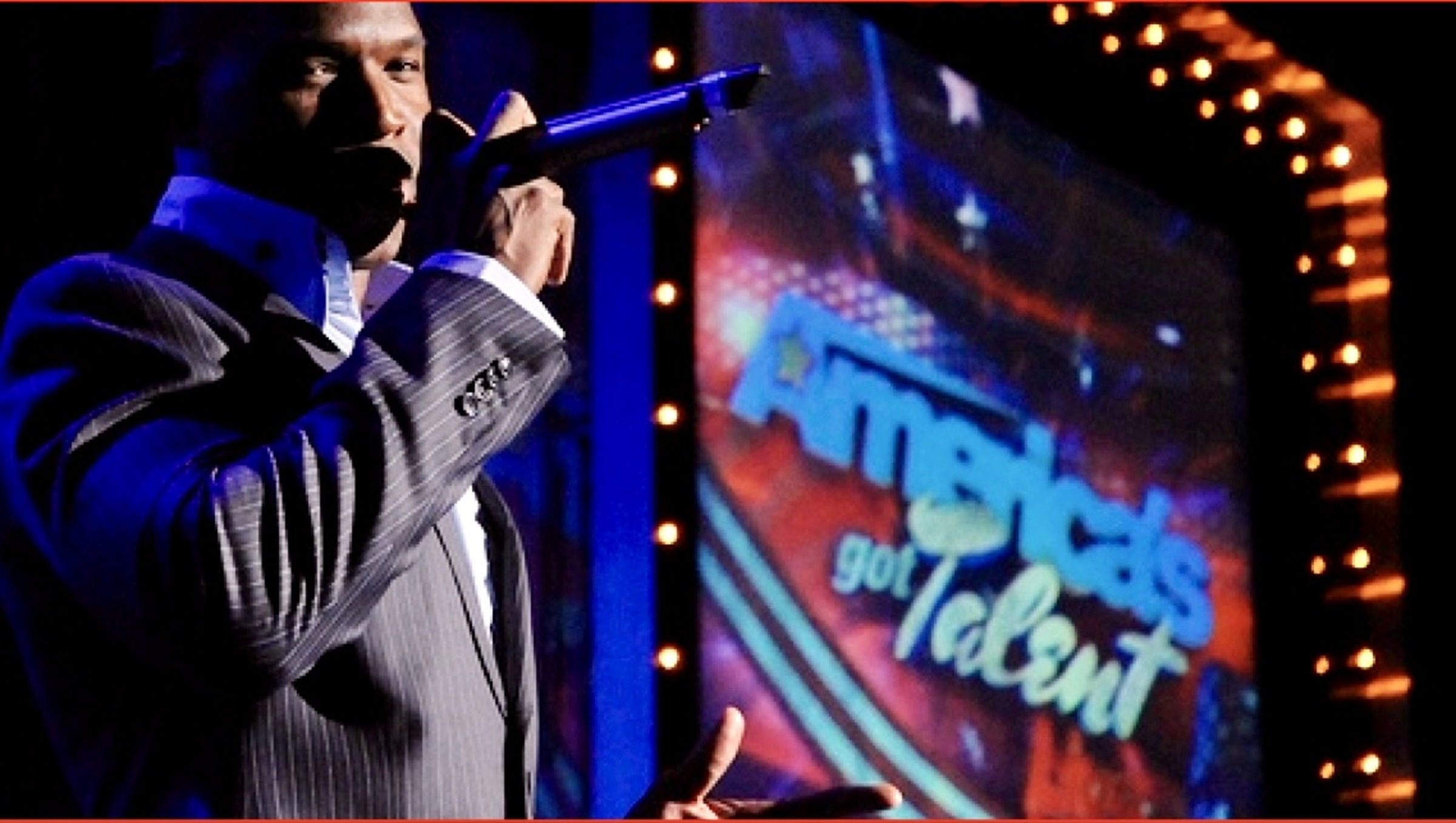 Lawrence Beamen singing on the America's Got Talent stage in a pinstripe suit