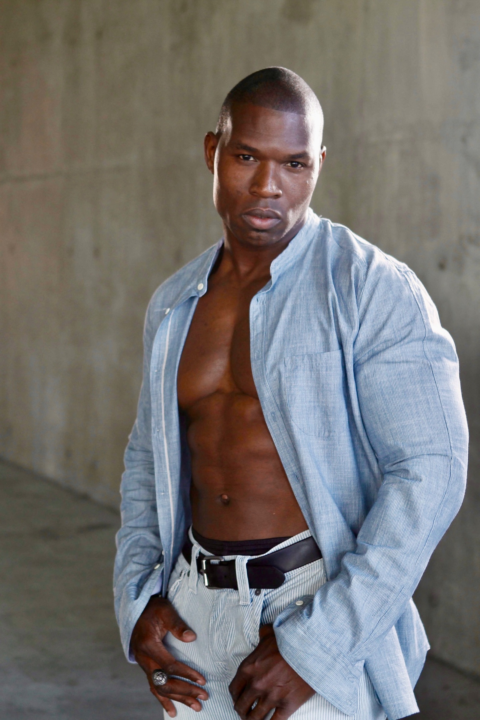 Lawrence Beamen in an open linen shirt against a concrete wall