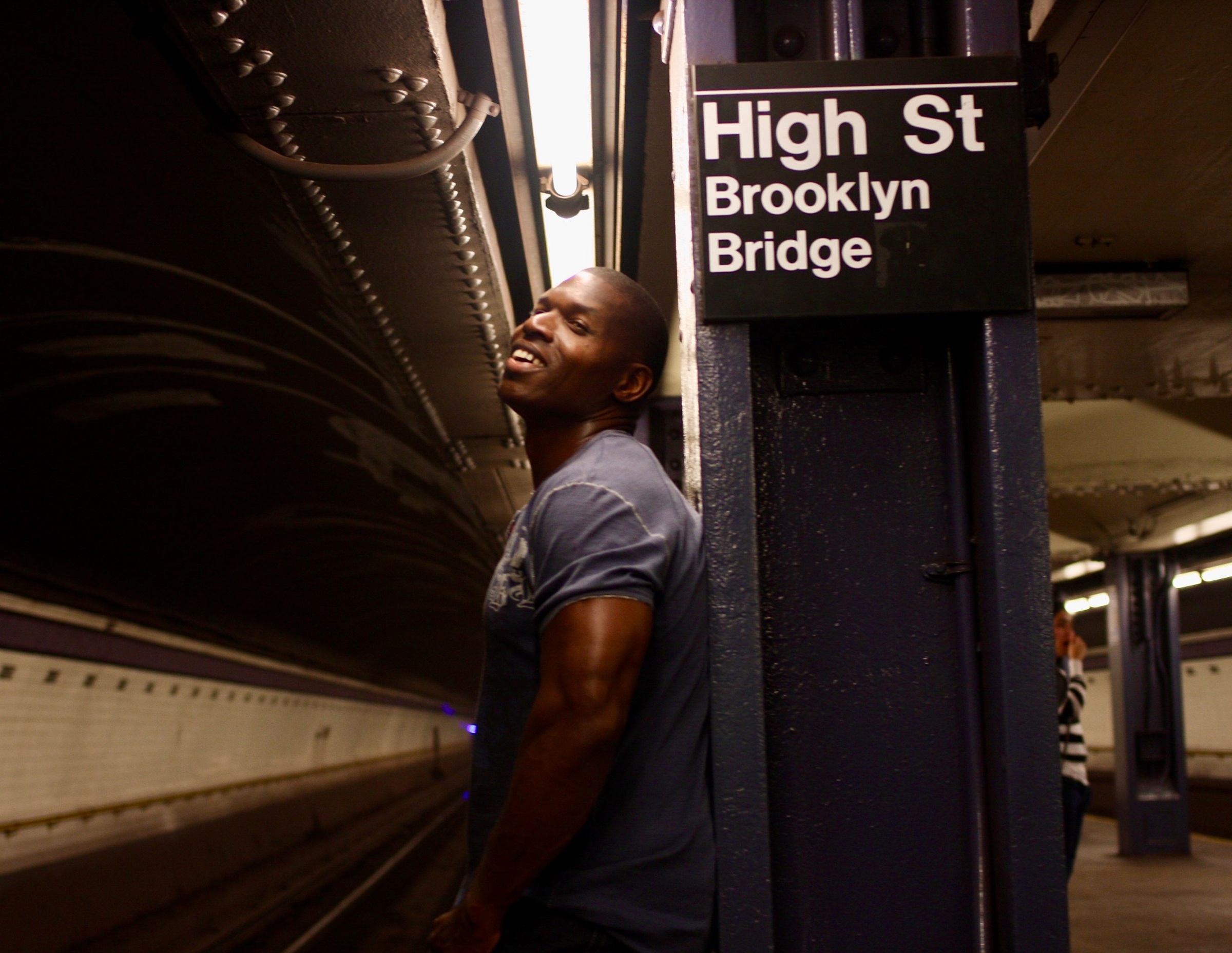 Lawrence Beamen laughing on a New York subway platform under the High St Brooklyn Bridge sign