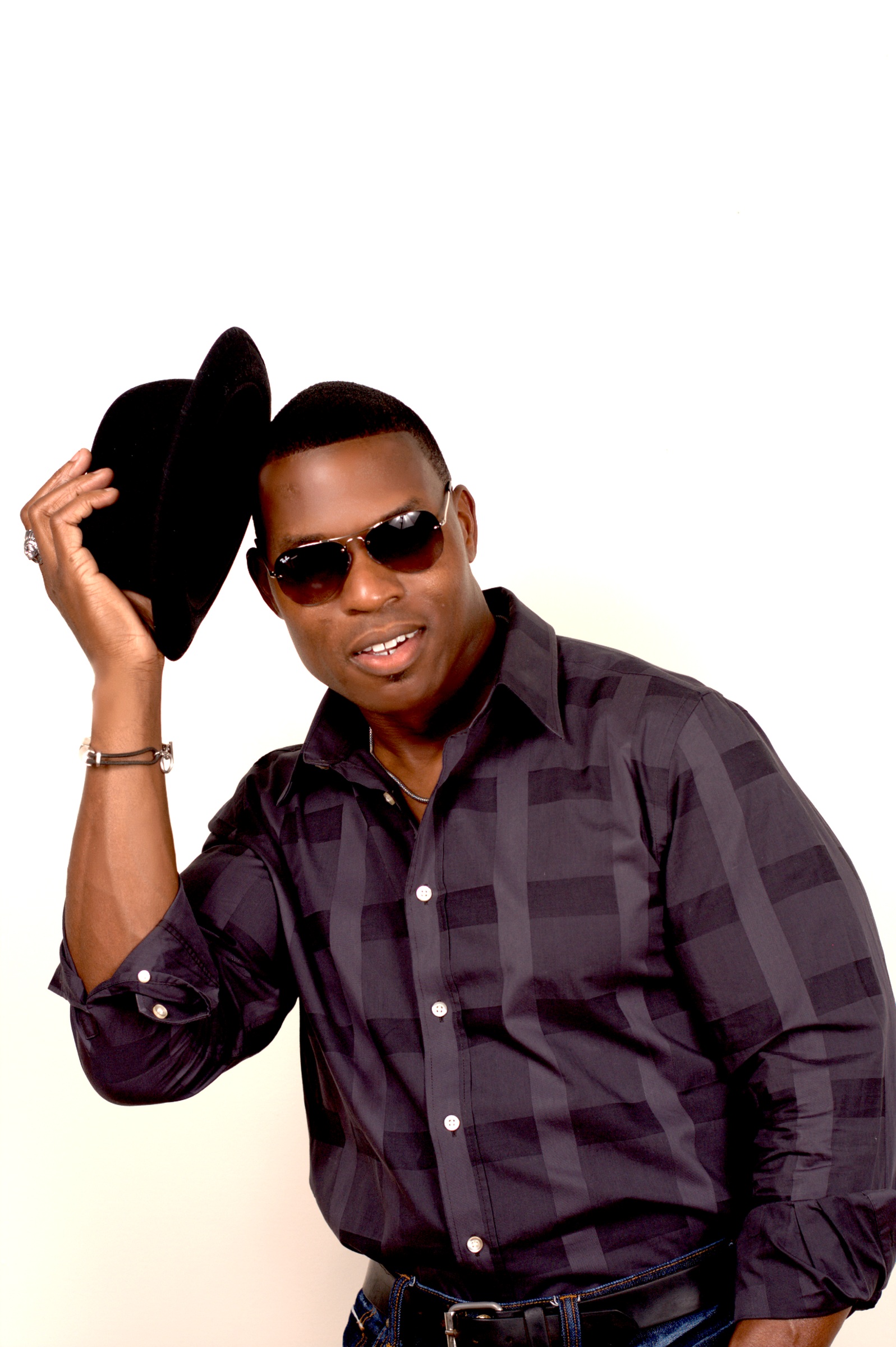 Lawrence Beamen tipping a black felt hat in sunglasses against a white backdrop