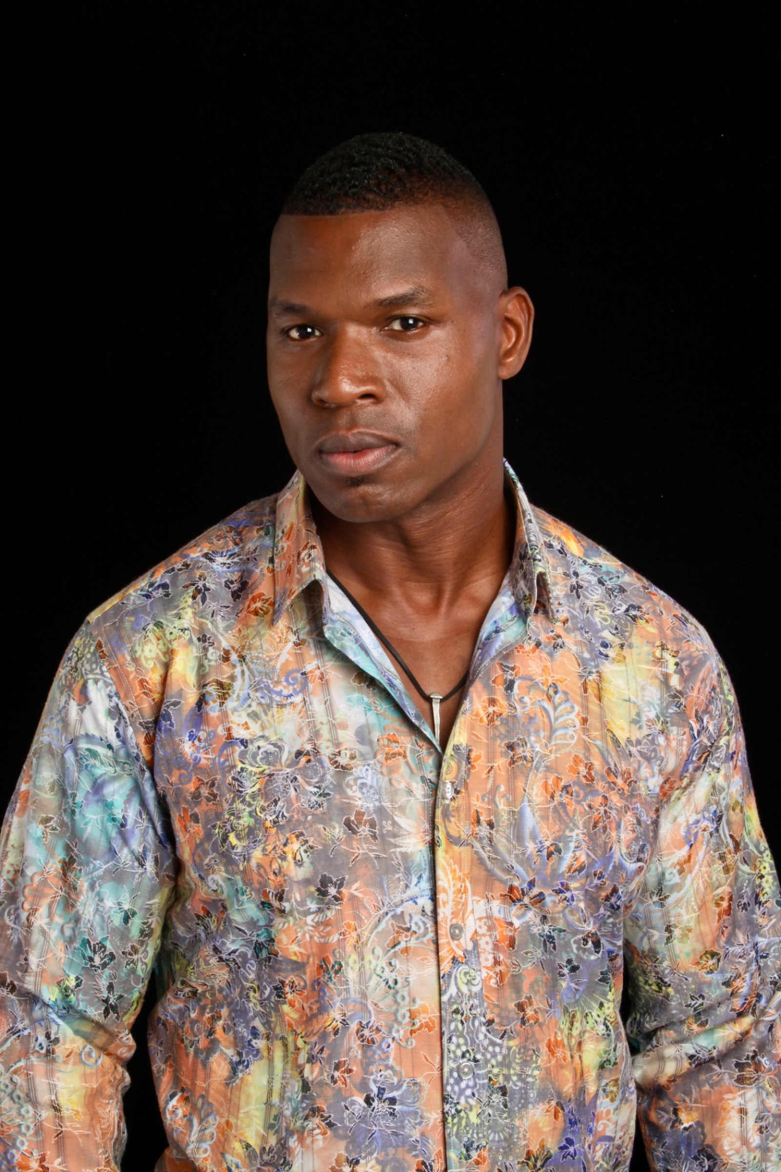 Lawrence Beamen in a floral patterned shirt against a black backdrop