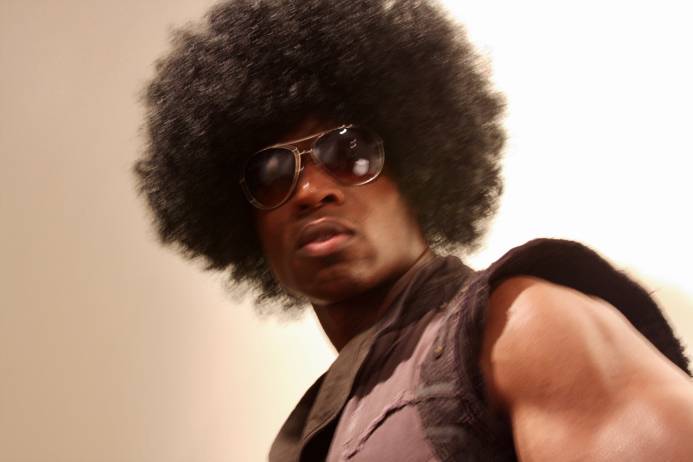 Close frame of Lawrence Beamen in an afro wig and aviator sunglasses
