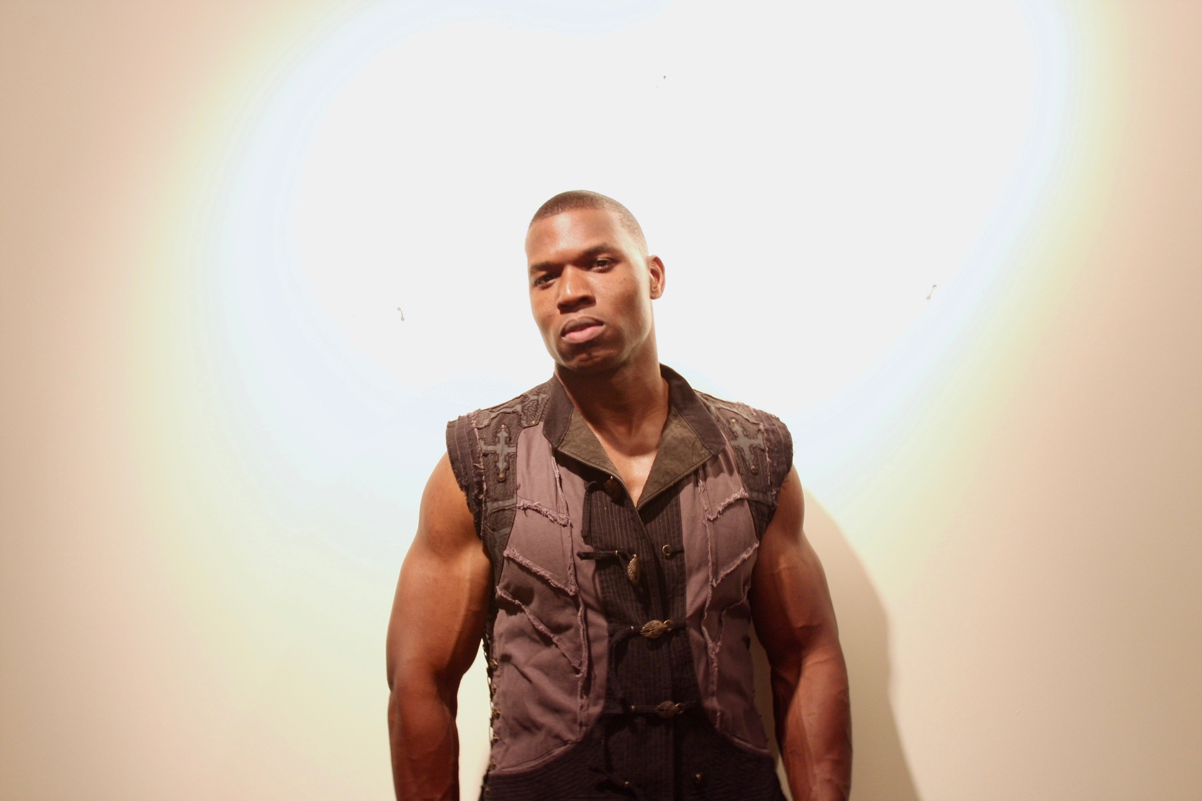 Lawrence Beamen standing in a sleeveless vest against a warm white wall