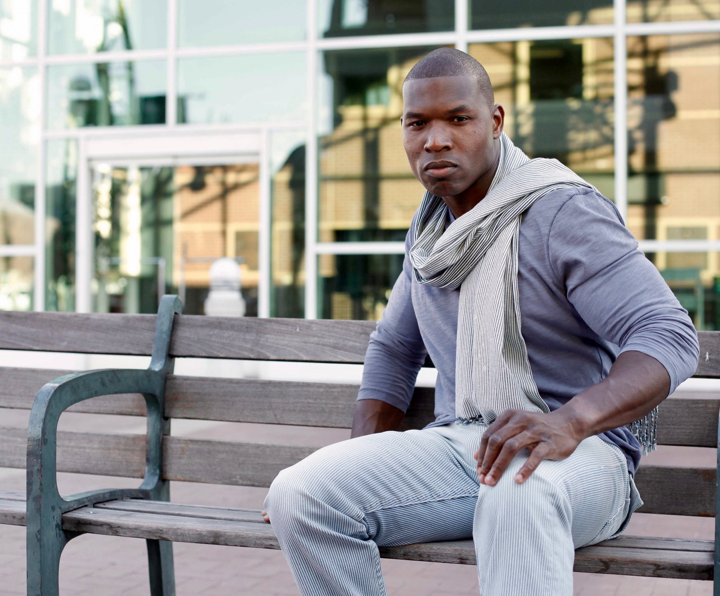 Lawrence Beamen seated on a city bench in a scarf and grey top