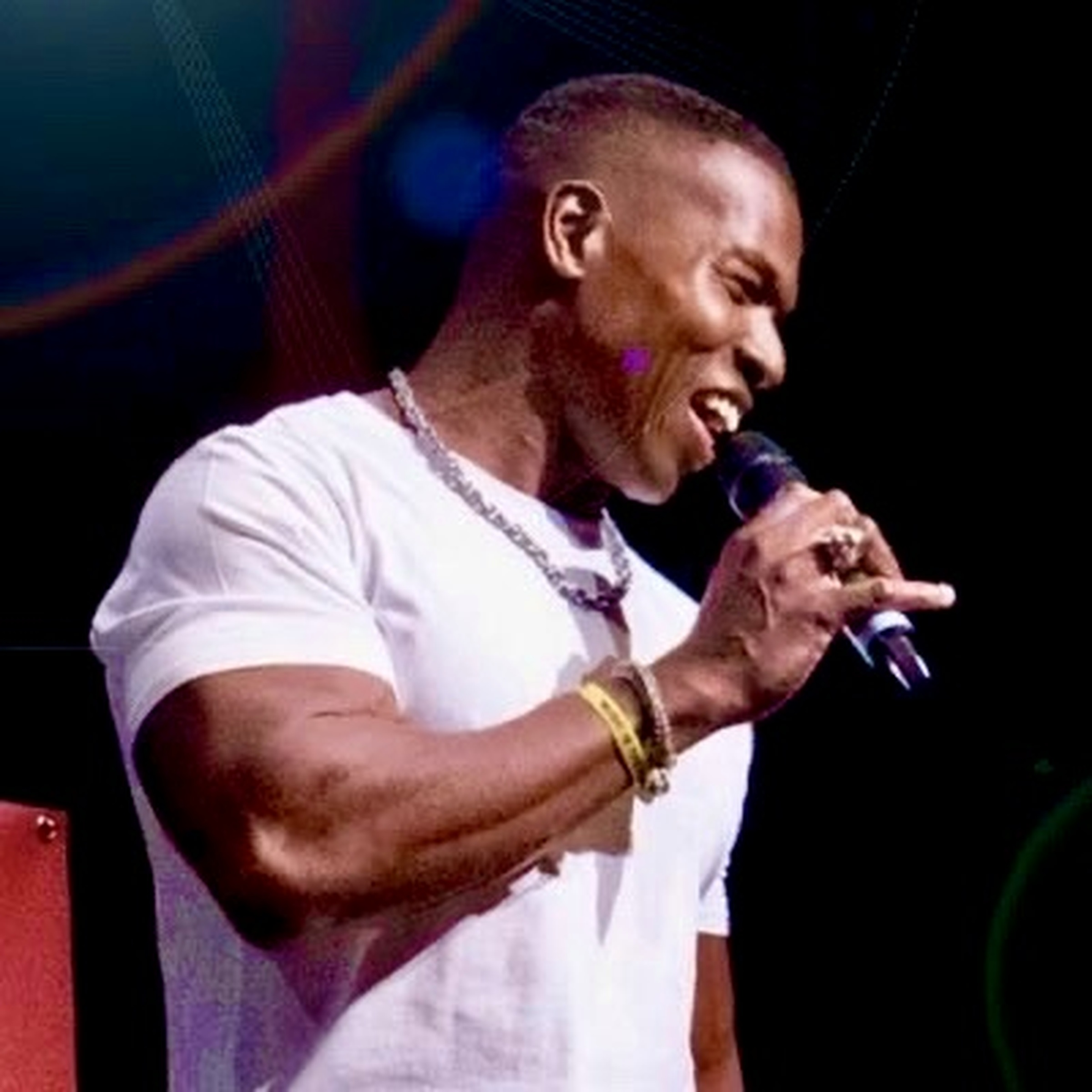 Lawrence Beamen singing into a handheld microphone in concert